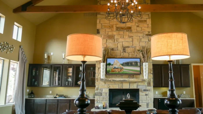 a large stone fireplace with two lamps and a television at The Anatole on MacArthur North